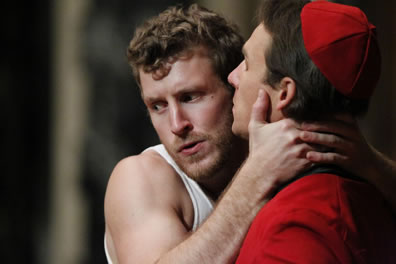 Ferdinand in tanktop t-shirt clasps the Cardinal in red vestry tight around the neck.