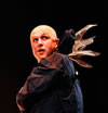 A man, bald, with a rain slickeer and fairy wings coming from the base of the hood